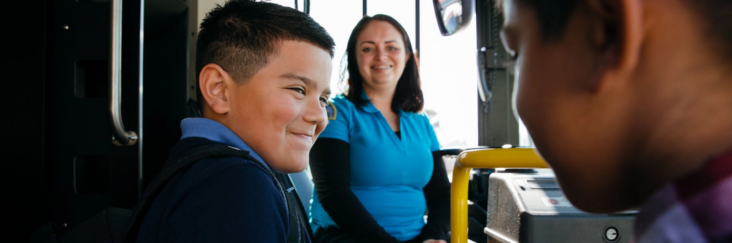 Boy getting on the bus with bus driver