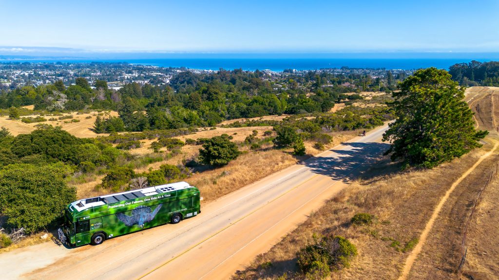 One ride at a time bus stopped overlooking the ocean and houses
 